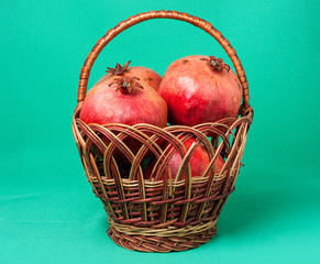Basket with pomegranates on green background