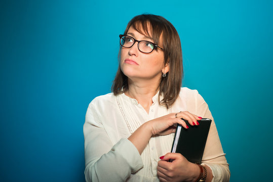 Woman in glasses with a book in your hands wondering about something