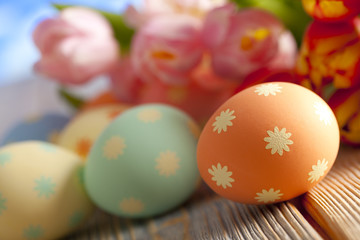 Colorful Easter eggs and spring flowers on sky background
