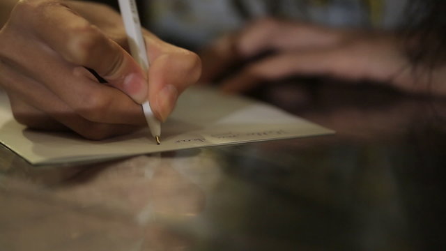 woman's hand with a nice manicure natural writing on sheets line by line.