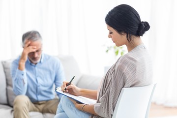 Female doctor writing on clipboard while consulting a man