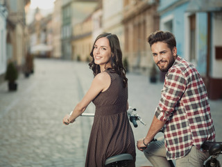 Fototapeta premium smiling couple on bicycles in town
