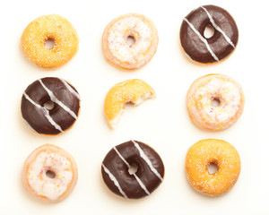 Verschiedene Donuts, mittlerer angebissen, auf weiss