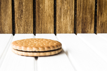 Single biscuit on a white wooden base and brown wooden background