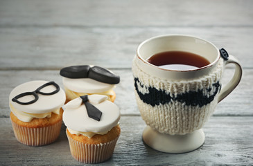 Delicious creative cupcakes and cup of tea on wooden table