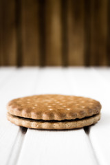 Single biscuit on a white wooden base and brown wooden background