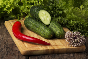 cucumbers with lettuce & chili pepper on wood