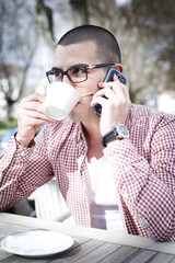 Attractive young man used morning sipping your coffee and talking on mobile.