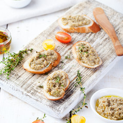 Bruschetta with green olives paste, tapenade on a white wooden background
