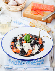 Black pasta spaghetti with cream sauce and smoked salmon Italian cuisine