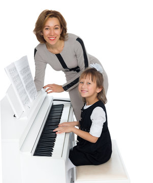 Mother and daughter playing on the white piano - Isolated on white background