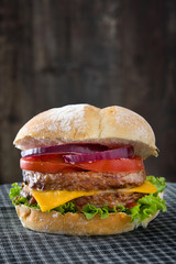 Delicious burger with cheddar cheese, tomato, lettuce and onion
