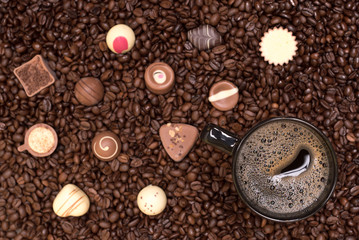 coffee beans background and black cup with pralines