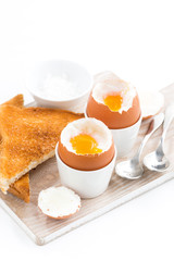 boiled eggs and crispy toasts on a wooden board, vertical