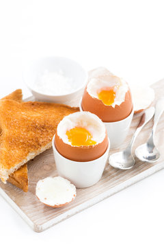 boiled eggs and crispy toasts on a wooden board, vertical