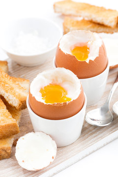 boiled eggs and toasts on a wooden board, vertical