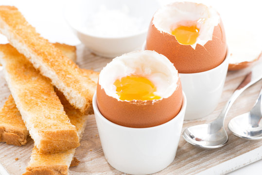 boiled eggs and toasts on wooden board, closeup, selective focus