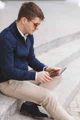 Young man with tablet computer sitting on stairs