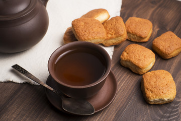 Square mug of tea with shortbread biscuits, on a brown table and a napkin