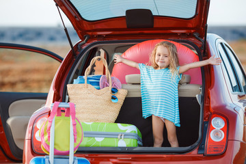 Portrait of a little girl sitting in the trunk of a car