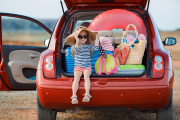 Little girl in straw hat sitting in the trunk of a car - 104284685