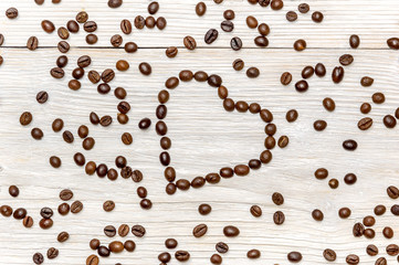 Heart made using coffee beans on a wooden background