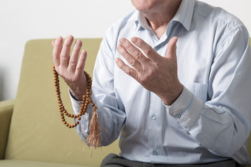 Praying hands of an old man holding rosary beads. S © Ravil Sayfullin