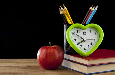 Apple, pencils, books and clock