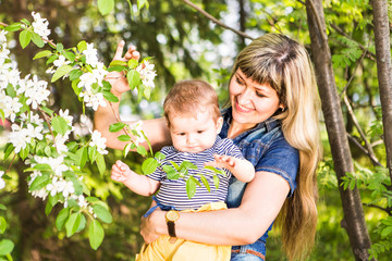 Happy woman and child in the blooming spring garden.  Mothers day holiday concept