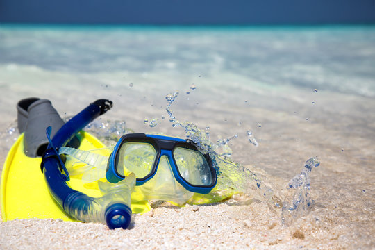Taucherbrille und Flossen am Strand liegend