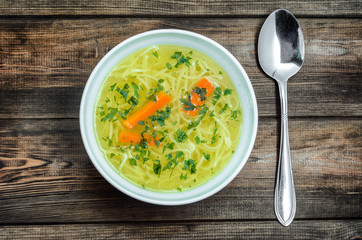Chicken broth soup with noodles on a wooden table. - obrazy, fototapety, plakaty