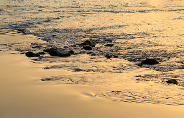 Rocks in a river with the sunlight reflected in the flowing water.