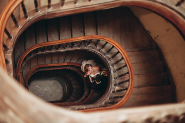 happy luxury wedding couple is standing and kissing on the stairs