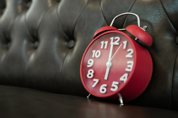 Red retro alarm clock on sofa.