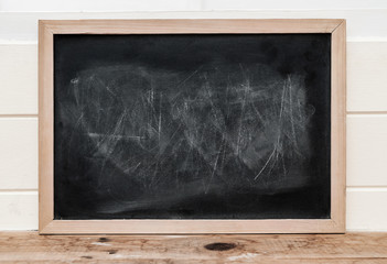 Close up a black chalkboard with wooden frame on wooden floor.