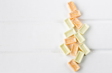 yellow and orange candies on white wooden background
