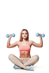 Fototapeta na wymiar Beautiful young girl with a sports body with dumbbells on a white studio background