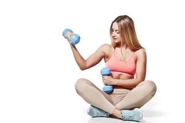 Beautiful young girl with a sports body with dumbbells on a white studio background