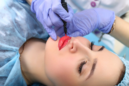 Cosmetologist making permanent makeup on woman's face