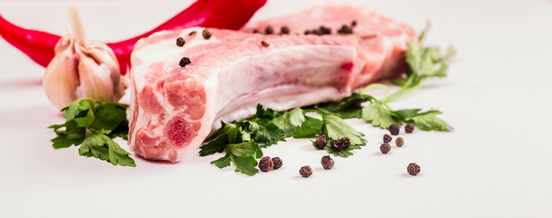juicy piece of meat on the bone with a pod of red pepper, parsley and garlic lie on a wooden table.
