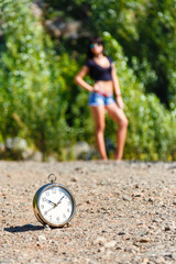 clock on the stone road and blurred girl at sunny day.
