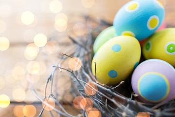 close up of colored easter eggs in nest on wood