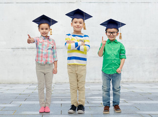 happy children in bachelor hats and eyeglasses