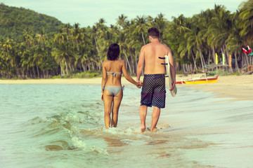 man and woman with a surfboard on the beach