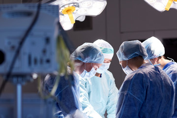 group of surgeons in operating room at hospital - Powered by Adobe