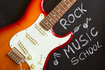 Red rock music electric guitar on blackboard background for music school and education concept, hobby and passion