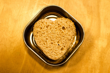 Bread Heart Sandwich / A heart-shaped bread sandwich sits in a metal food container.