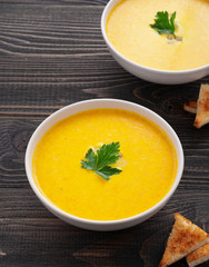 pumpkin soup with parsley leaf on dark wooden surface