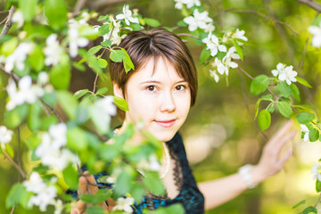 Romantic young woman in the spring garden among apple blossom
