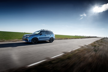 Obraz na płótnie Canvas Blue car fast drive on asphalt road at daytime